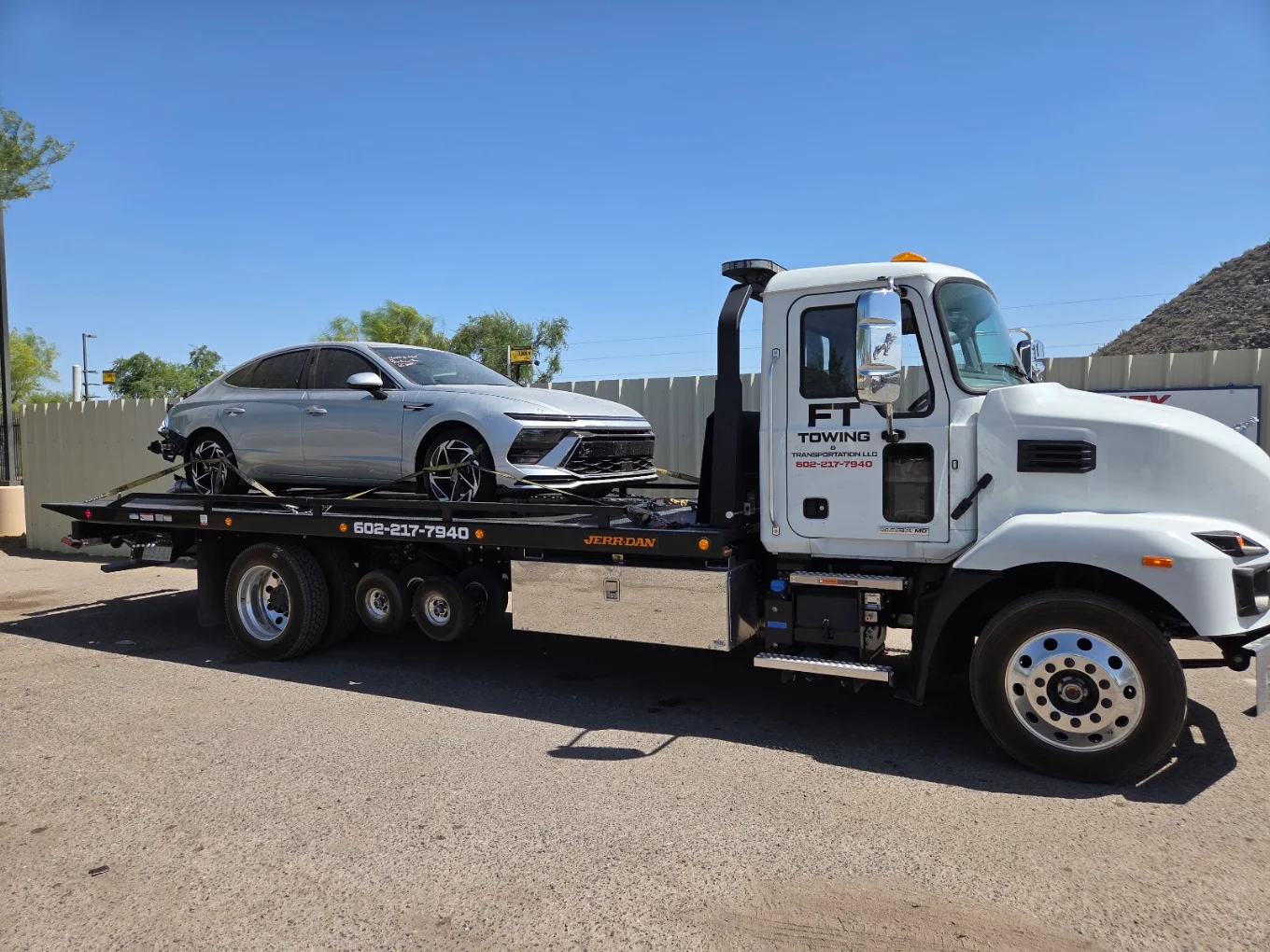 FT Towing rollback truck transporting a silver sedan